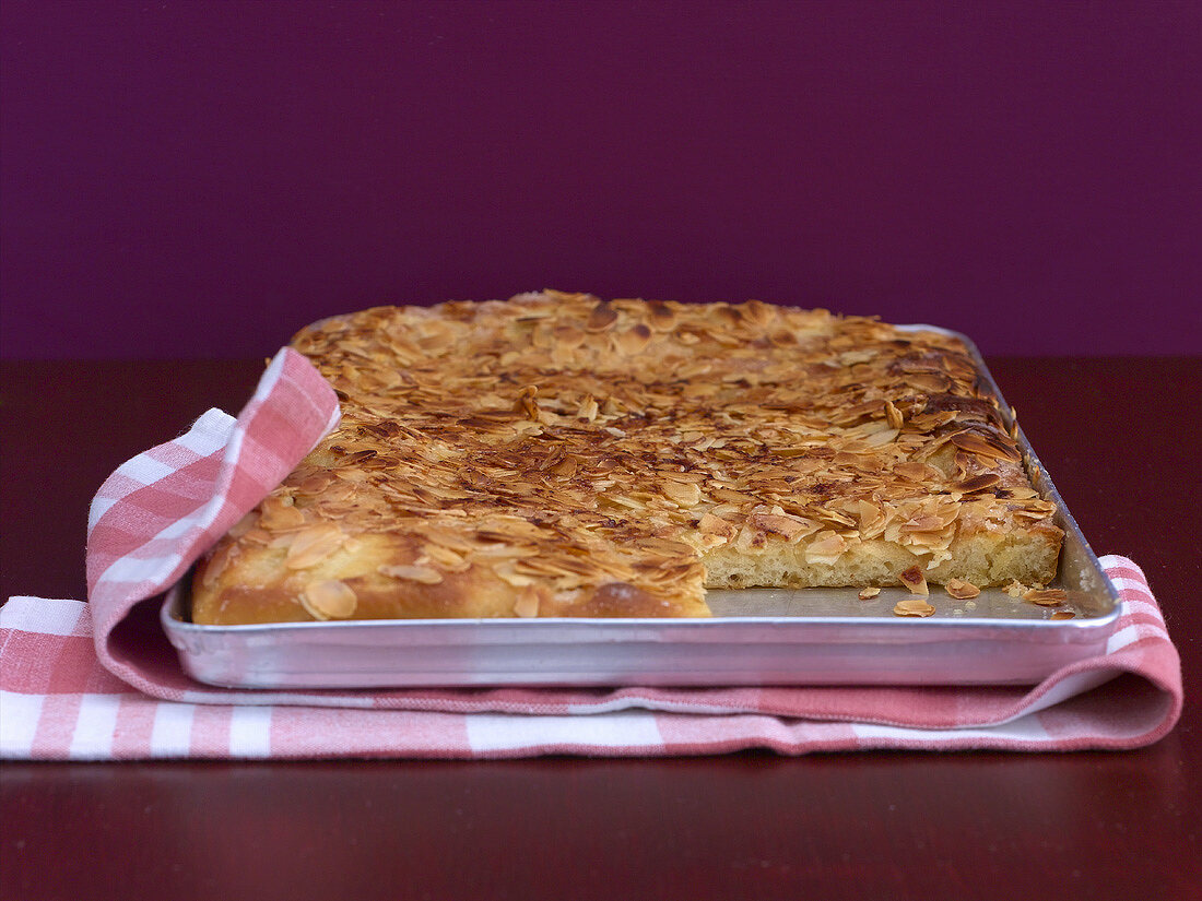 Tray-baked cake with almonds on a baking tray
