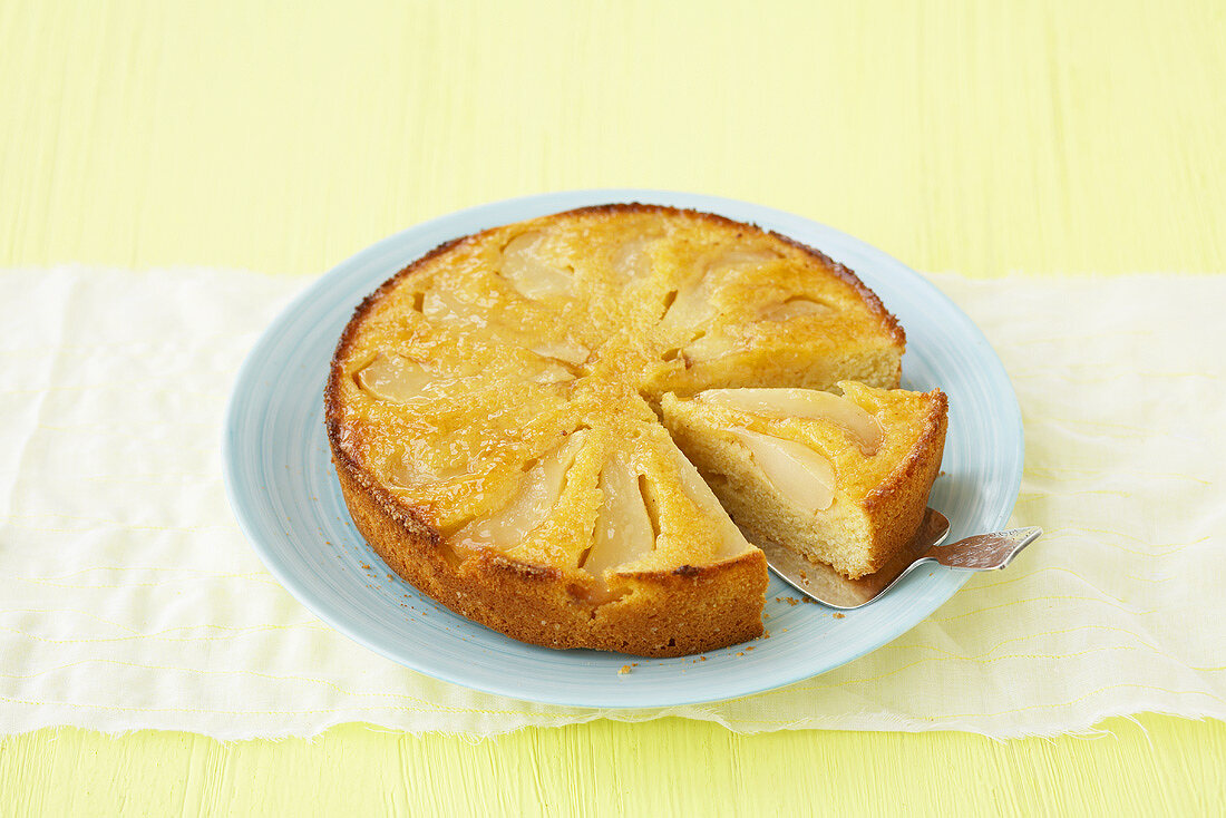 A pear and polenta cake with a piece cut