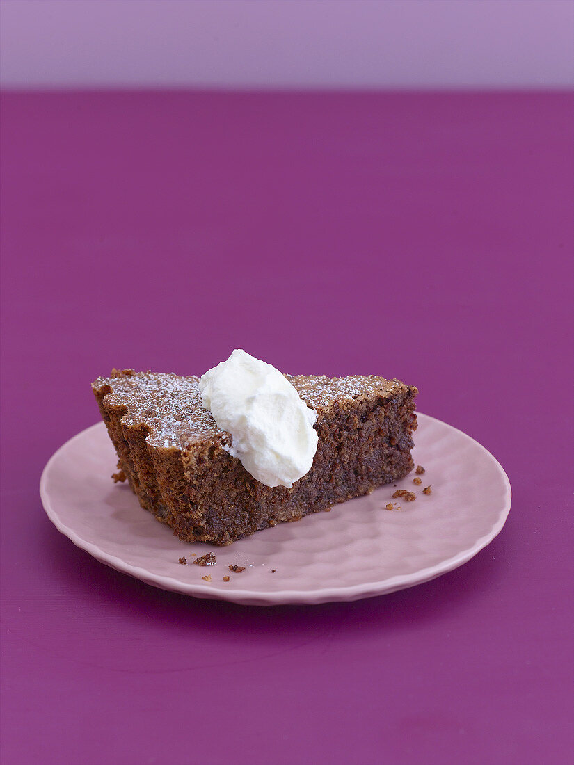 A piece of chocolate almond cake with whipped cream