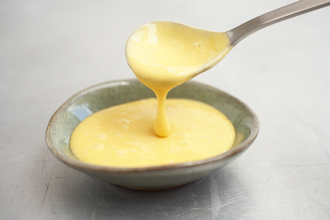 Pouring mayonnaise into a dish from a spoon