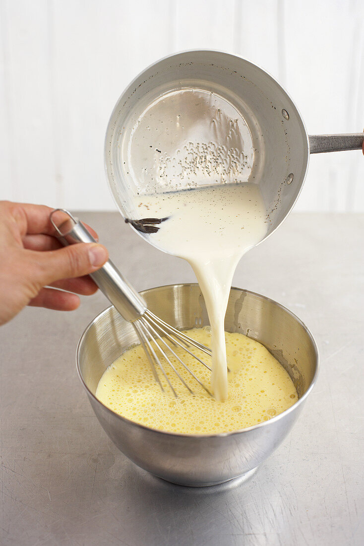 Pouring vanilla milk into egg yolk mixture for custard