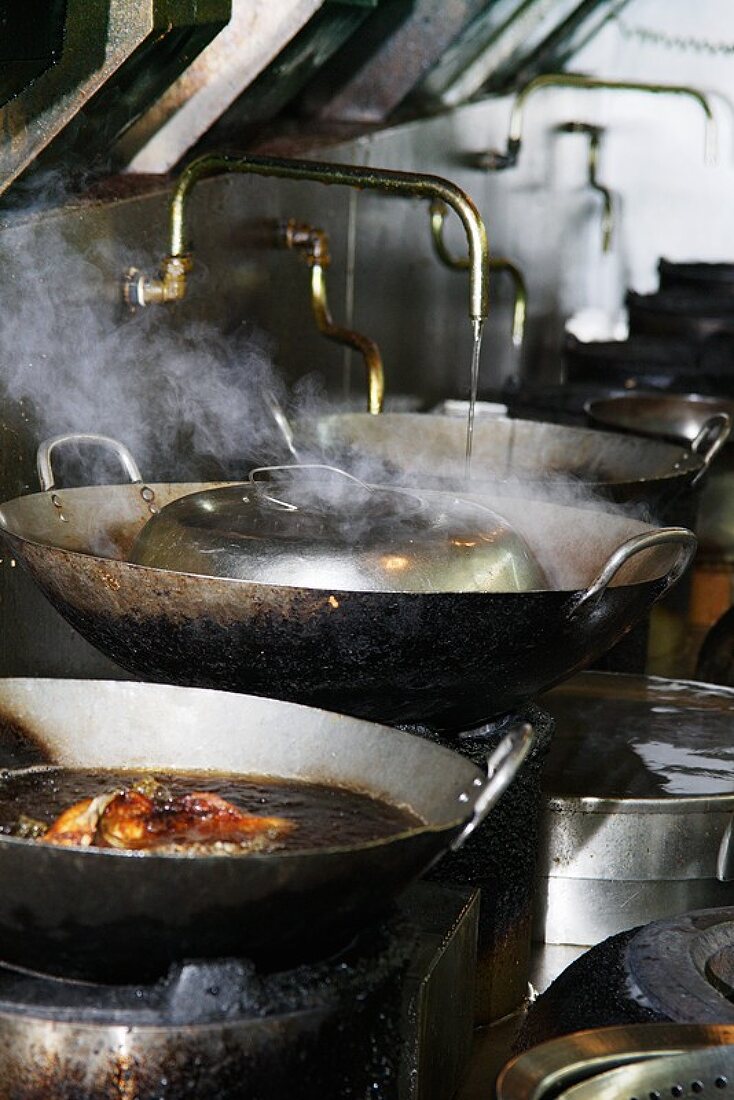 Steaming woks in Chinese kitchen