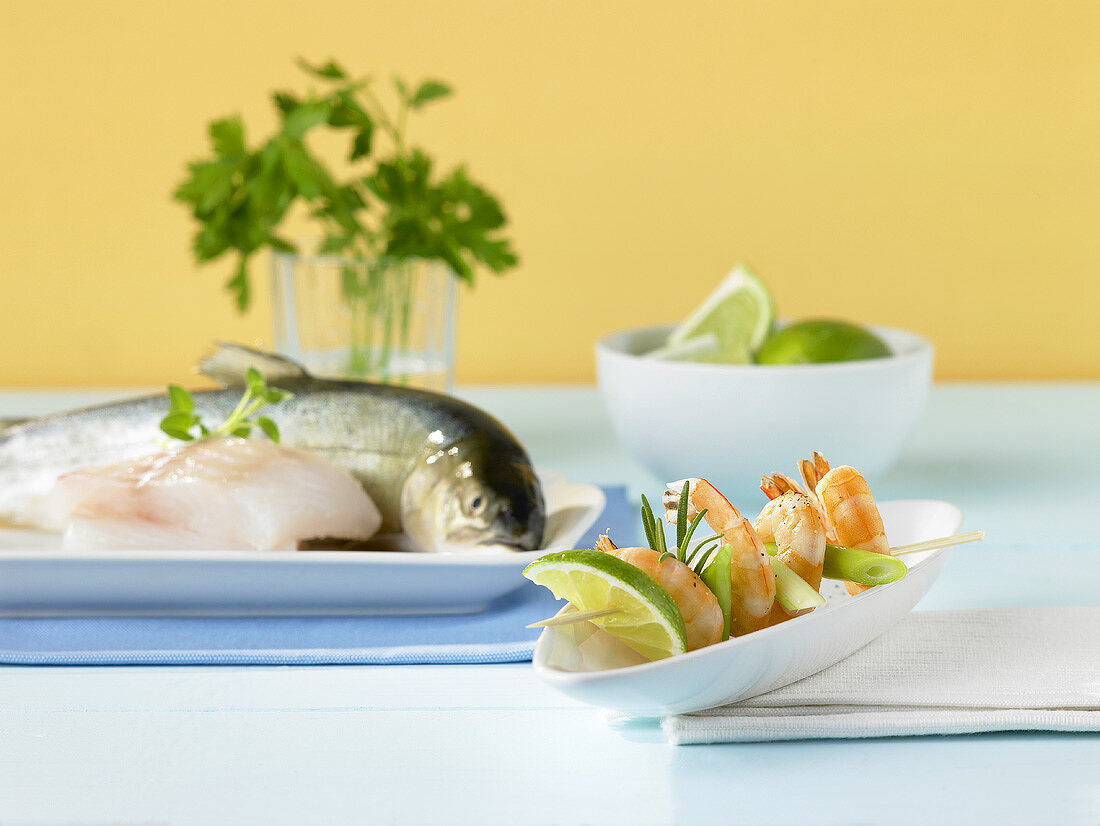 Skewered prawns with lime slices and spring onions