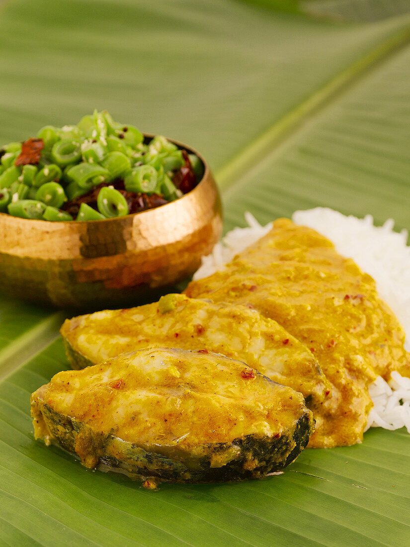 Fish curry with beans and rice on banana leaf (India)