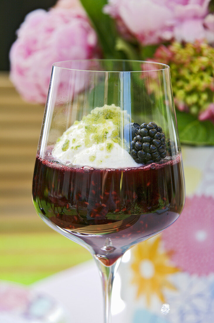 A glass of berry compote with yoghurt and basil