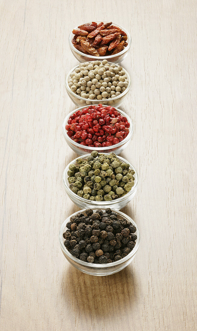 Four different types of peppercorns and dried chillies