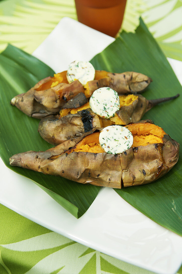 Baked sweet potatoes with herb butter on banana leaf