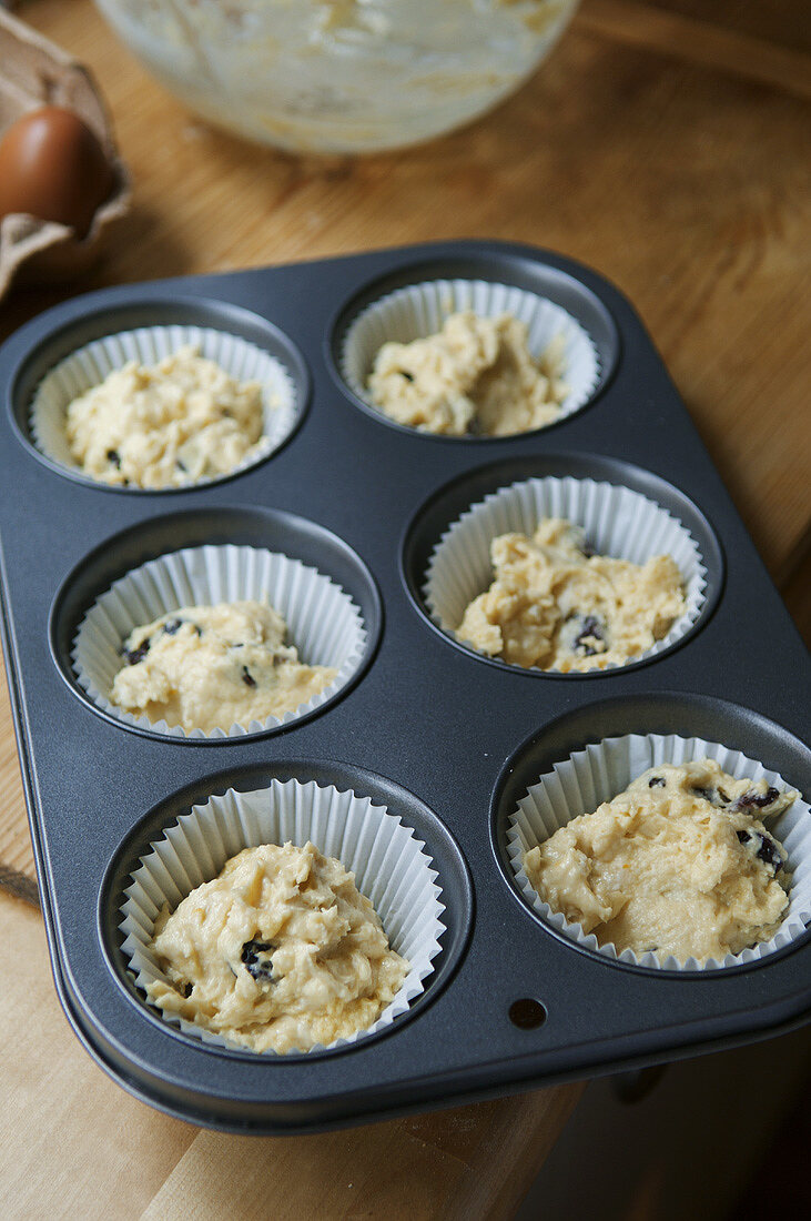 Muffin mixture with dried cherries in a muffin tin (UK)