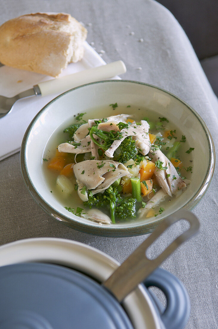 Chicken and vegetable soup in a soup plate with baguette