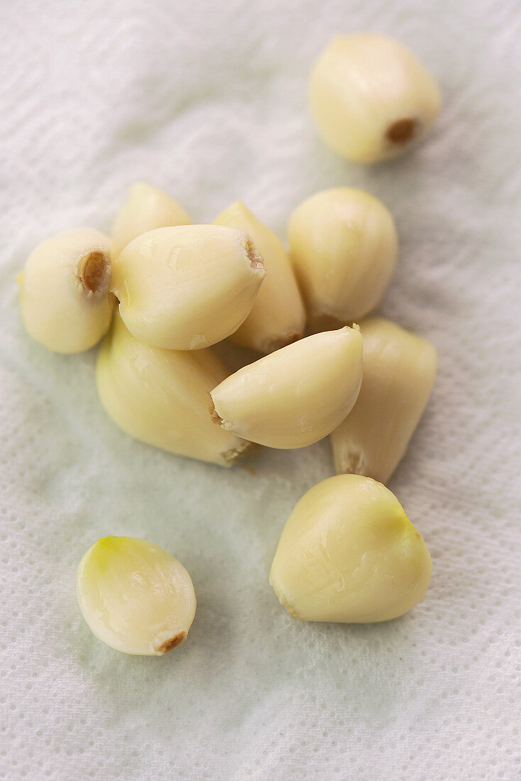Several peeled garlic cloves on paper towel