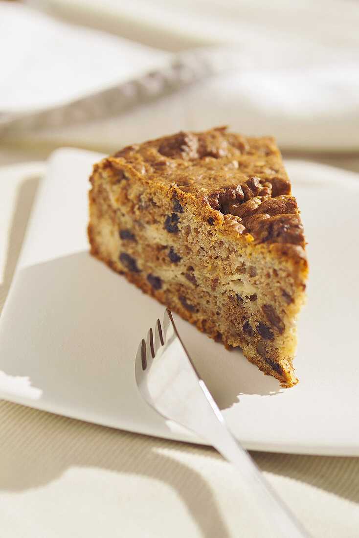 A piece of apple cake with raisins and nuts