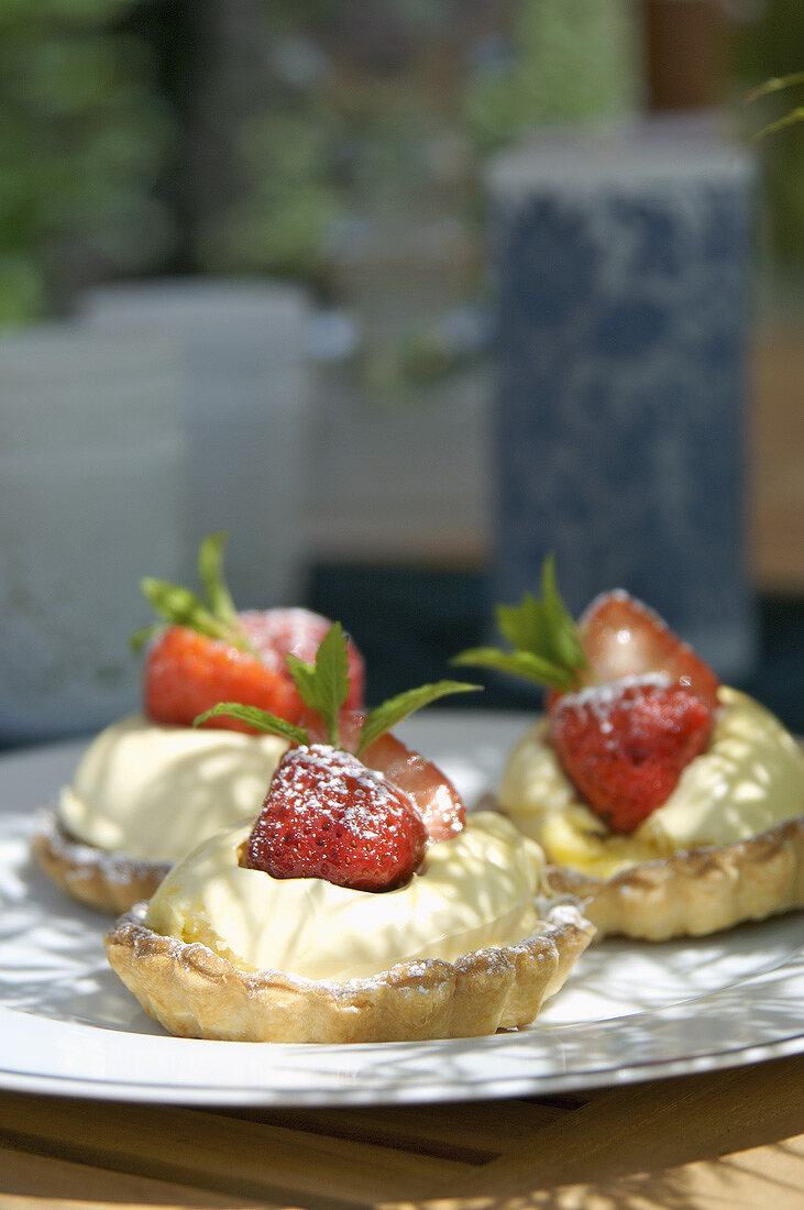 Drei Tarteletts mit clotted Cream und marinierten Erdbeeren
