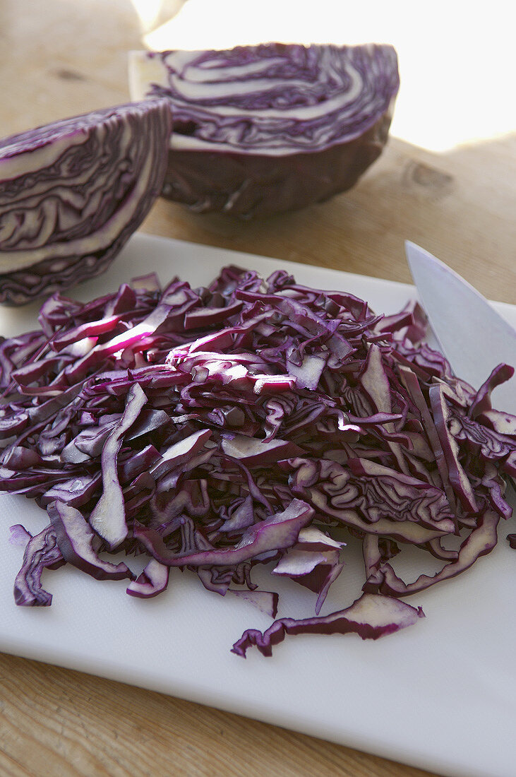 Shredded red cabbage with knife and chopping board