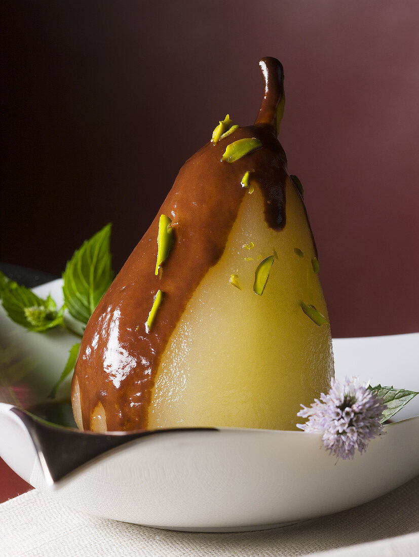 Poached pear with chocolate sauce and pistachios