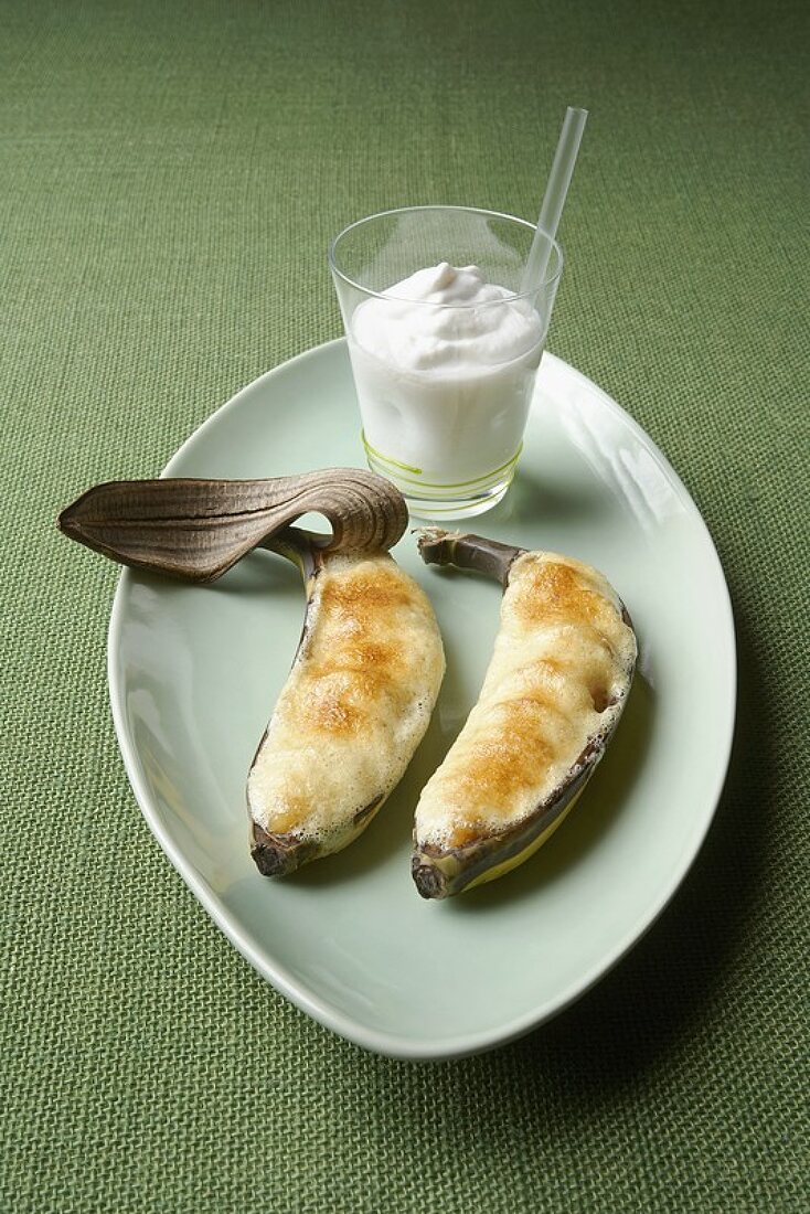 Two baked bananas in a dish with coconut milkshake