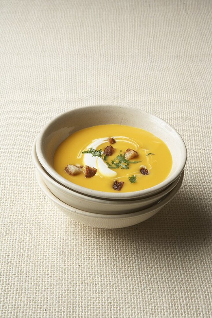A bowl of pumpkin cream soup with herb croutons