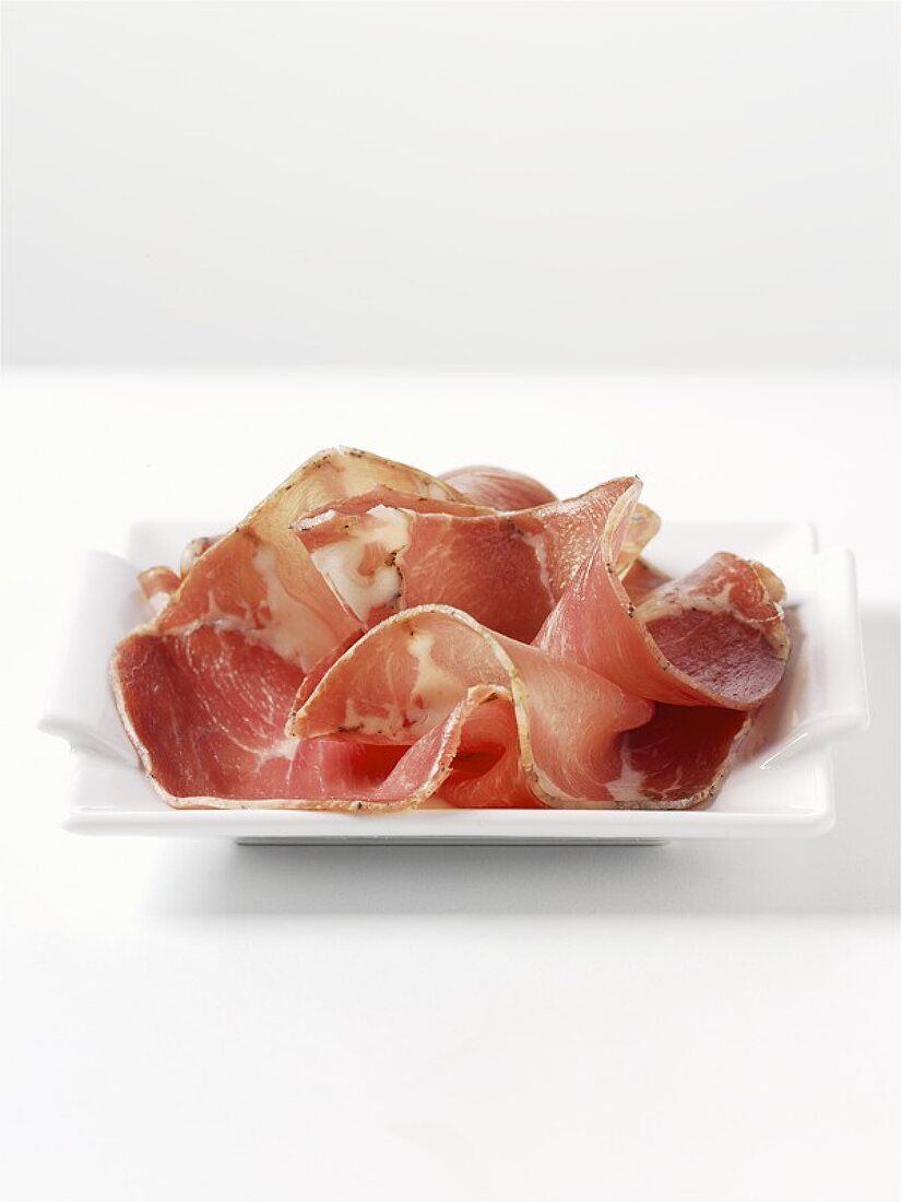 Sliced Coppa ham on a china plate