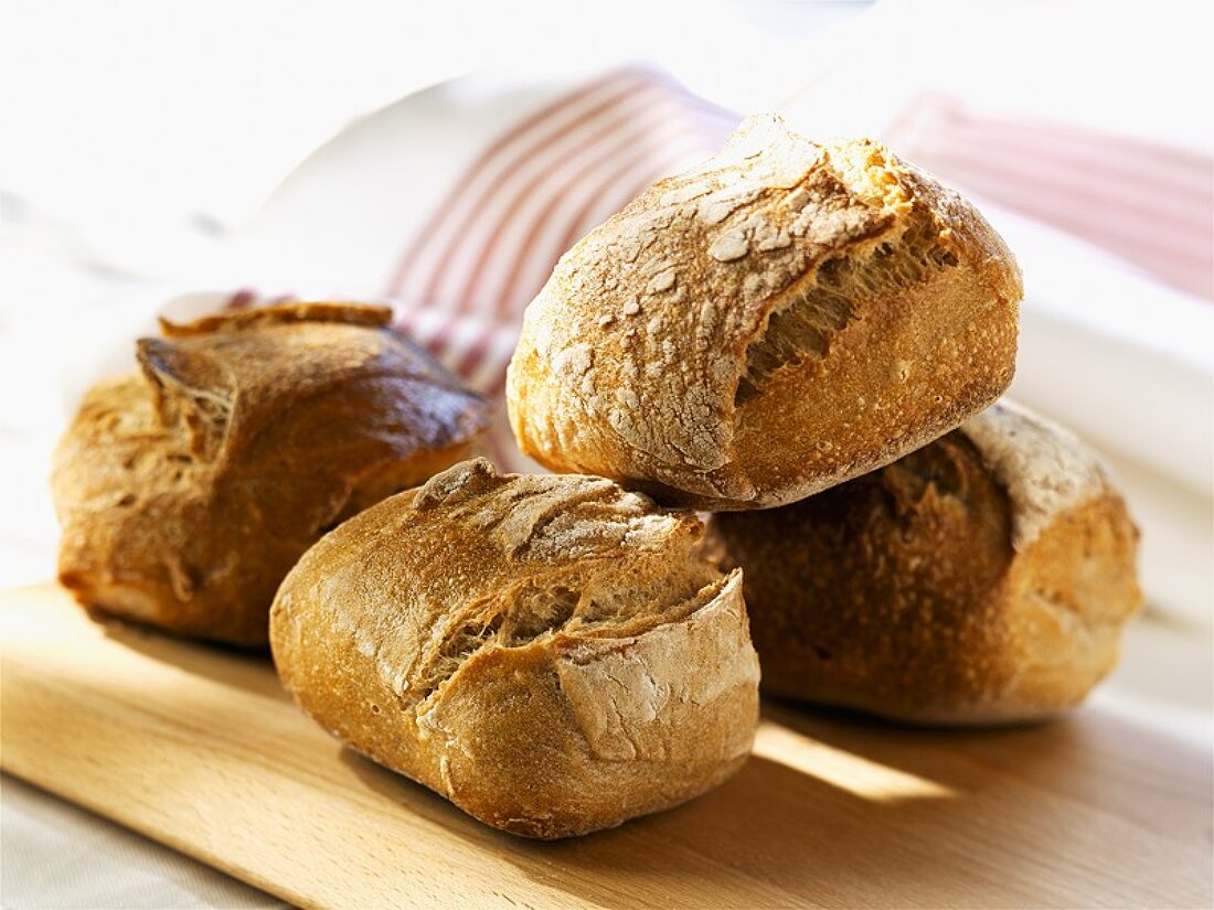 Four wholemeal rolls on a wooden board