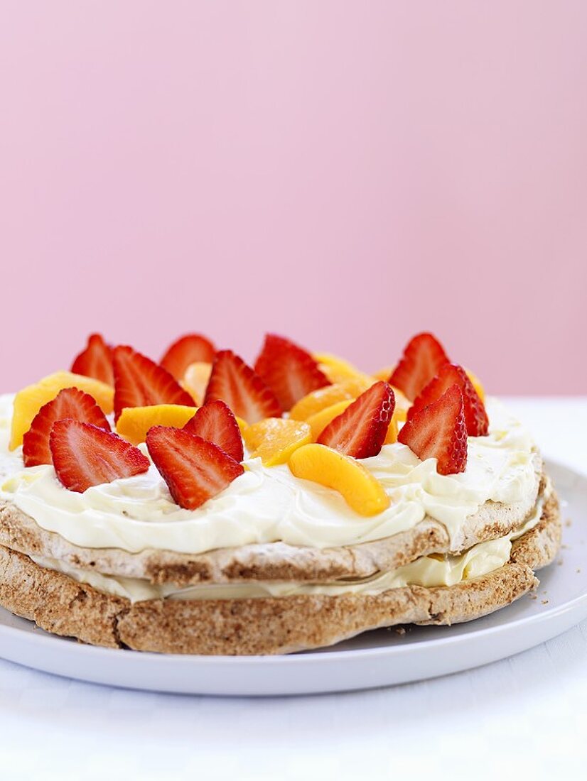 Haselnuss-Baisertorte mit Erdbeeren, Pfirsich und Schlagsahne