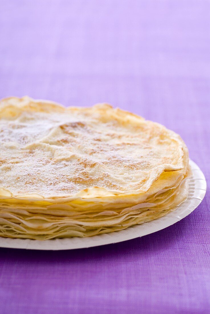 Several sugared crêpes on a plate
