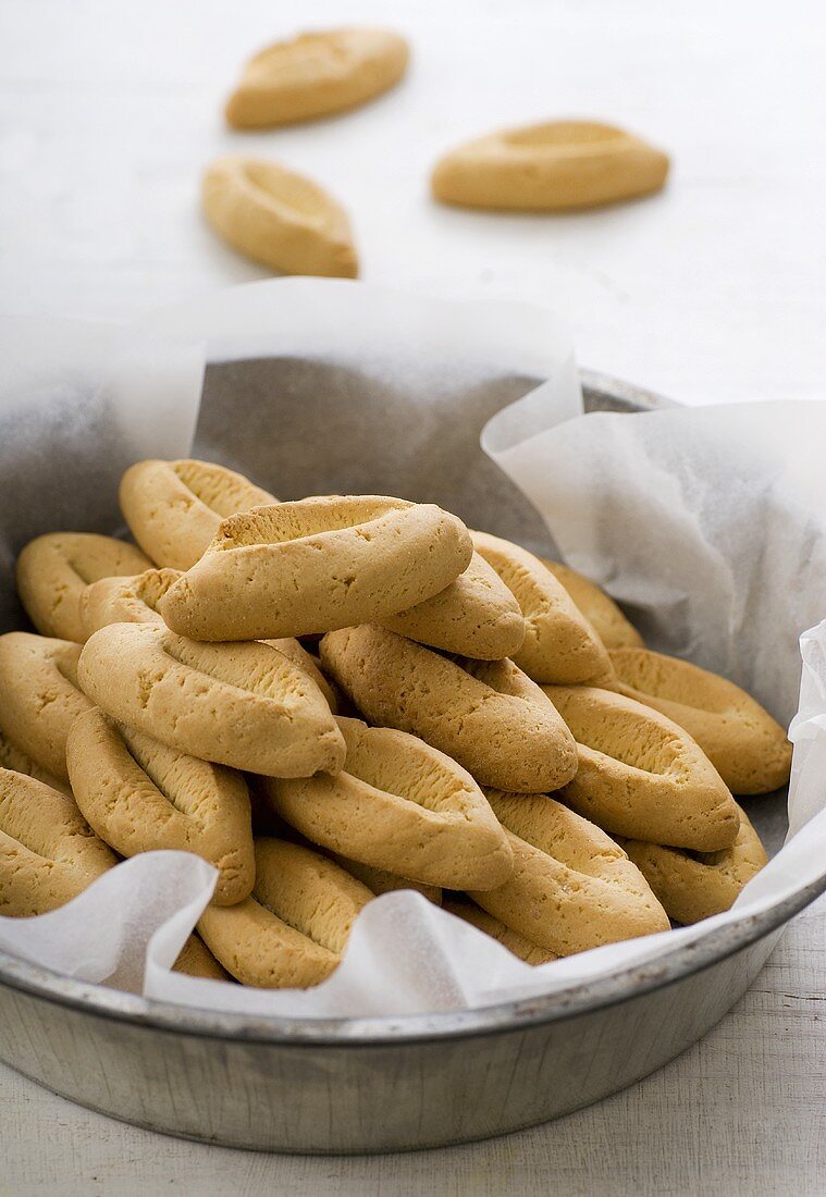 Boat-shaped orange biscuits in a baking tin