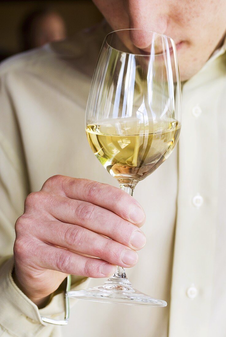 Mann riecht an einem Glas Weißwein
