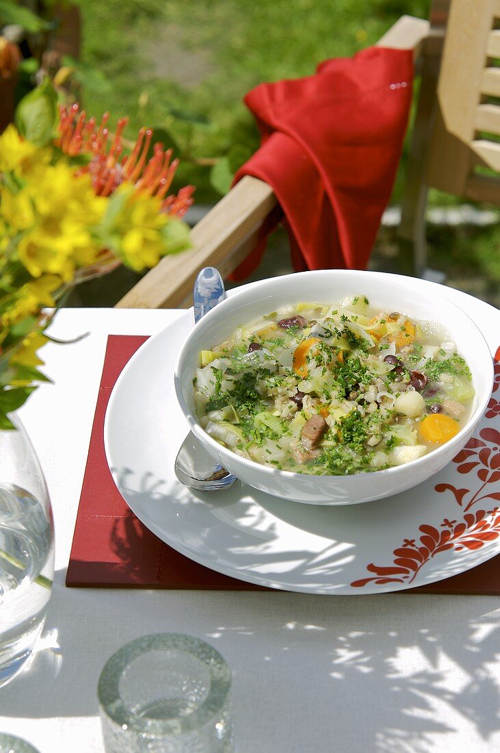 Gemüse-Reissuppe mit Schinken im Freien