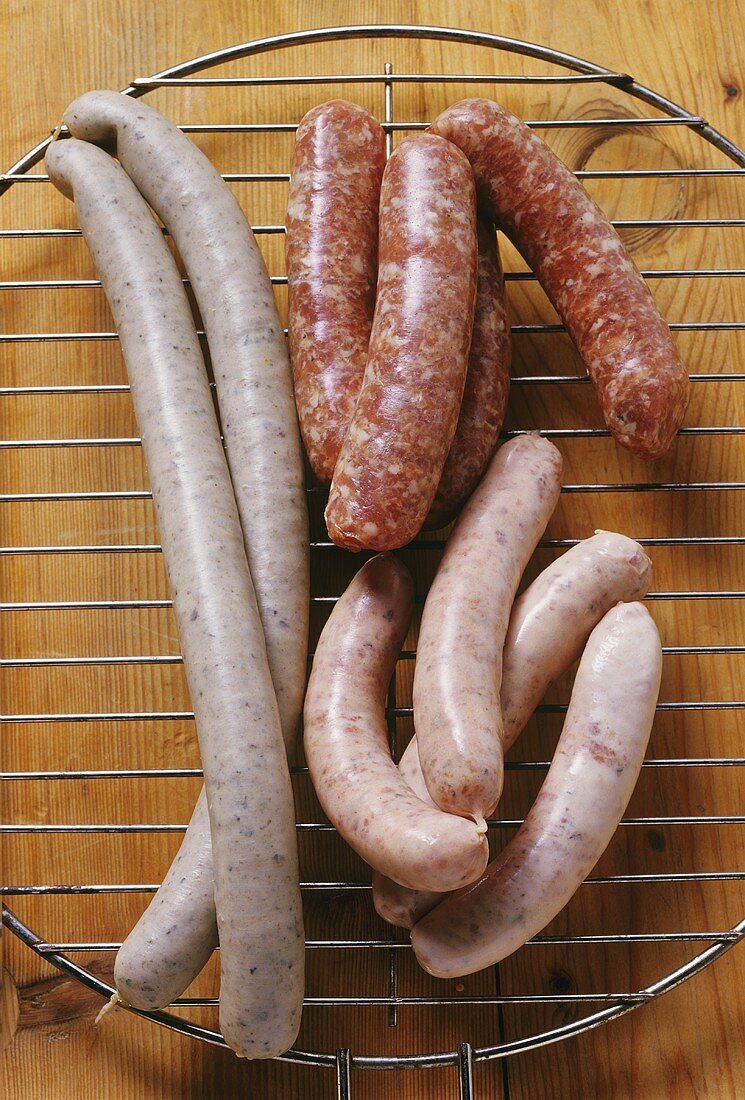 Various fresh sausages on a grill rack