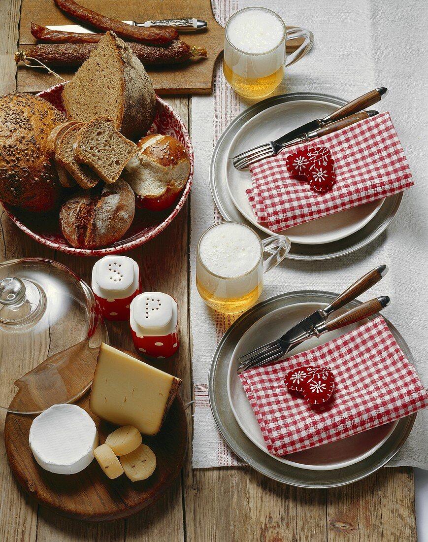 Gedeckter Brotzeit-Tisch mit Käse, Brot, Wurst und Bier