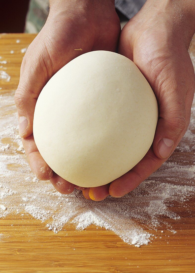 Hands holding a ball of pasta dough