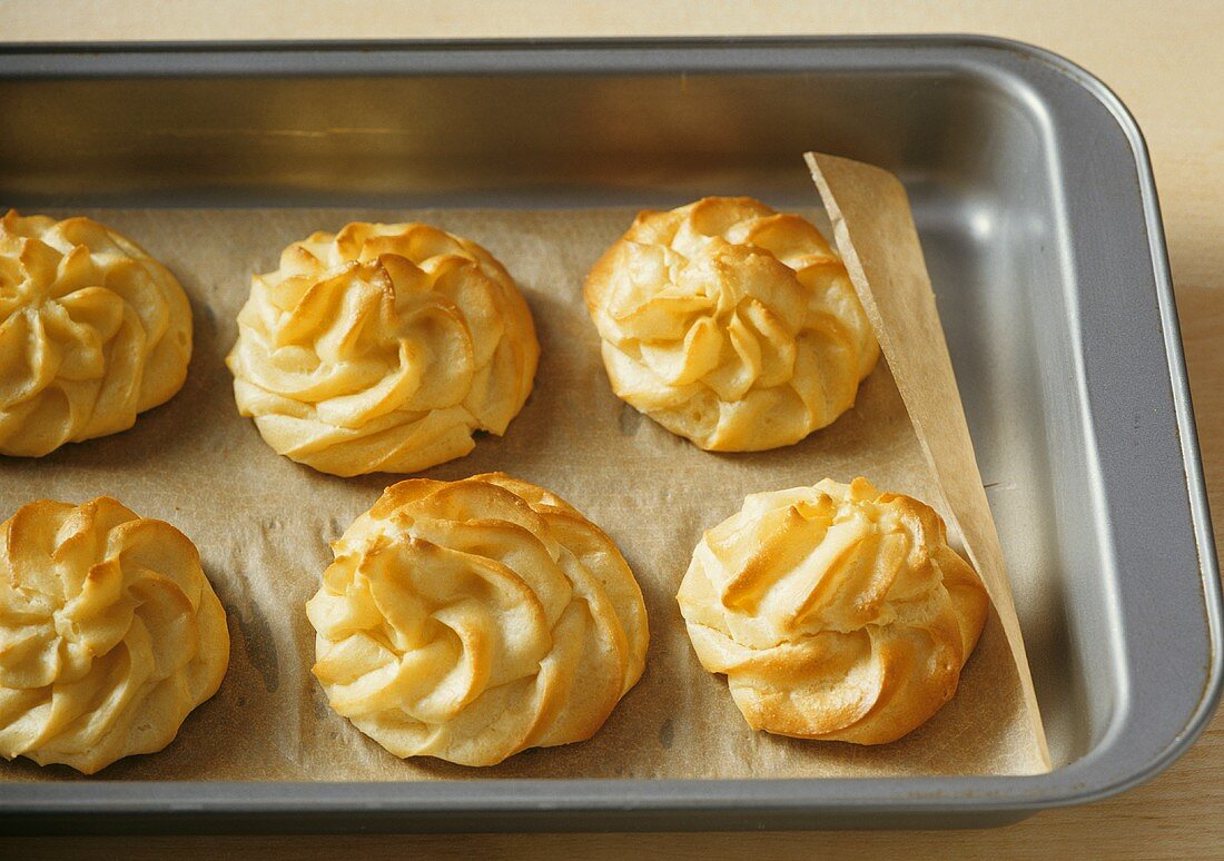 Six profiteroles on baking tray lined with baking parchment