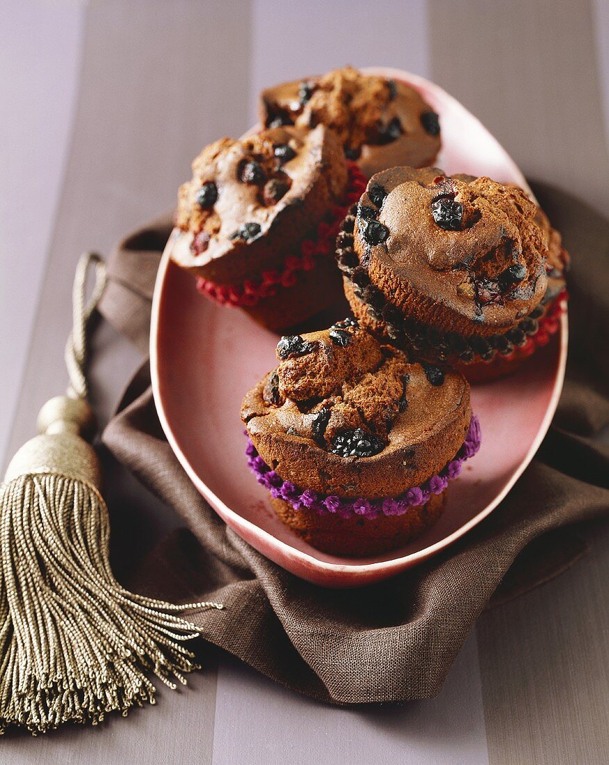 Vier Schokoladen-Muffins mit Beeren auf einer Platte