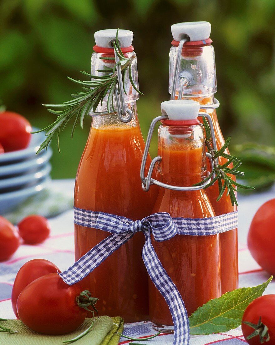 Tomato juice in 3 flip-top bottles, tomatoes, rosemary, bay