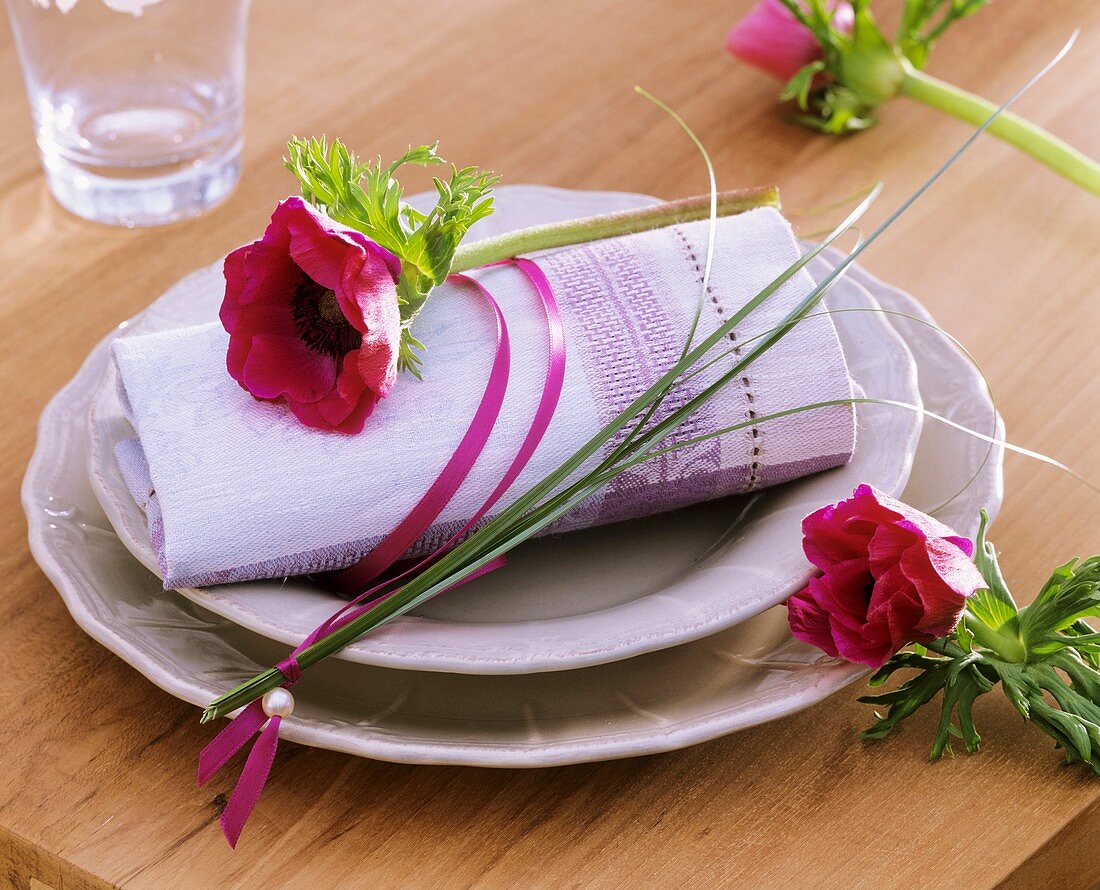 Place-setting with poppy anemone and bear grass on napkin