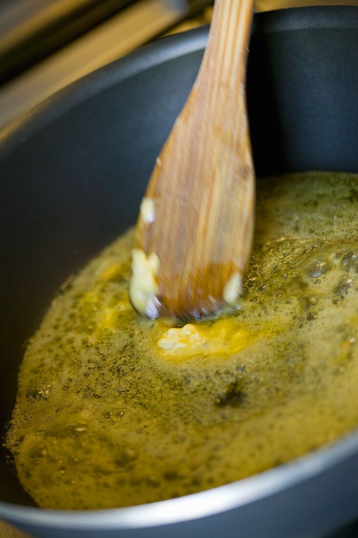 Butter schmilzt in einer Pfanne mit Kochlöffel