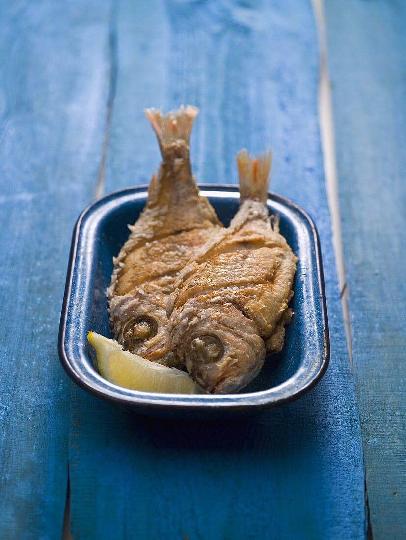 Two fried snappers in an enamel dish