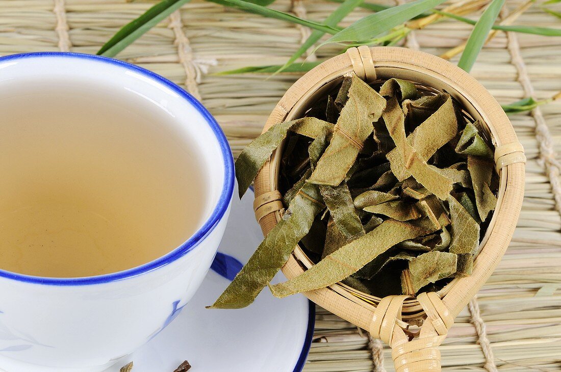 Dried loquat leaves in tea strainer with a cup of tea