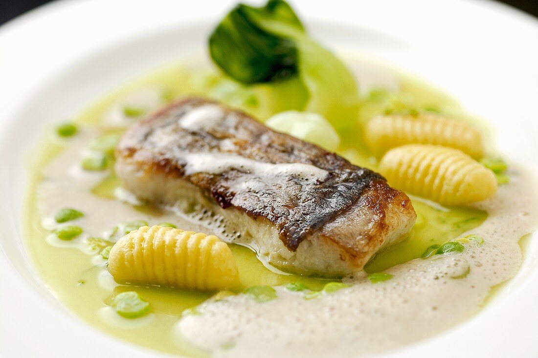 Fried sea bass with peas, pak choi and gnocchi