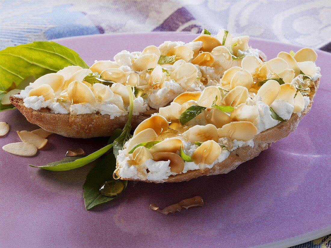 Geröstetes Weißbrot mit Ziegenfrischkäse, Honig und Mandeln