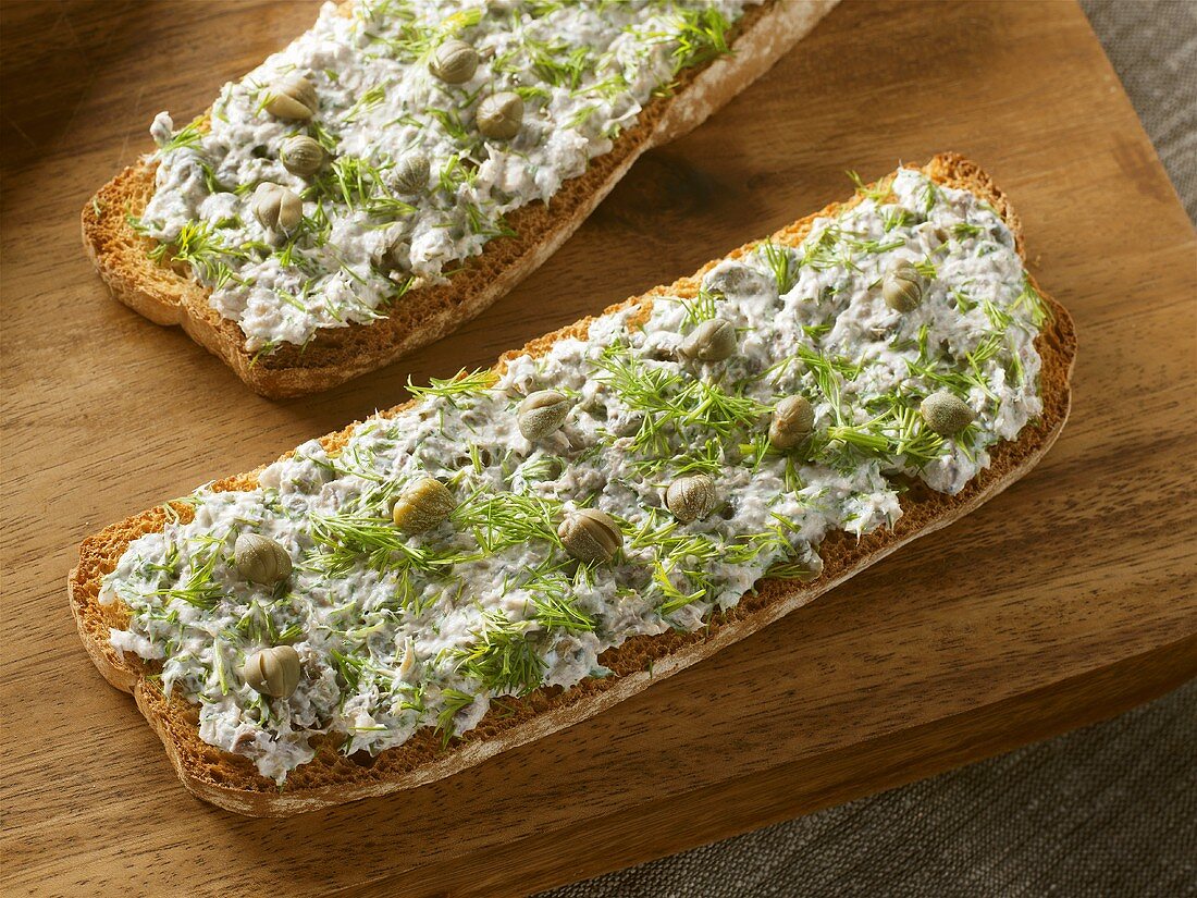 Soft cheese, sardines, capers and dill on slices of toast