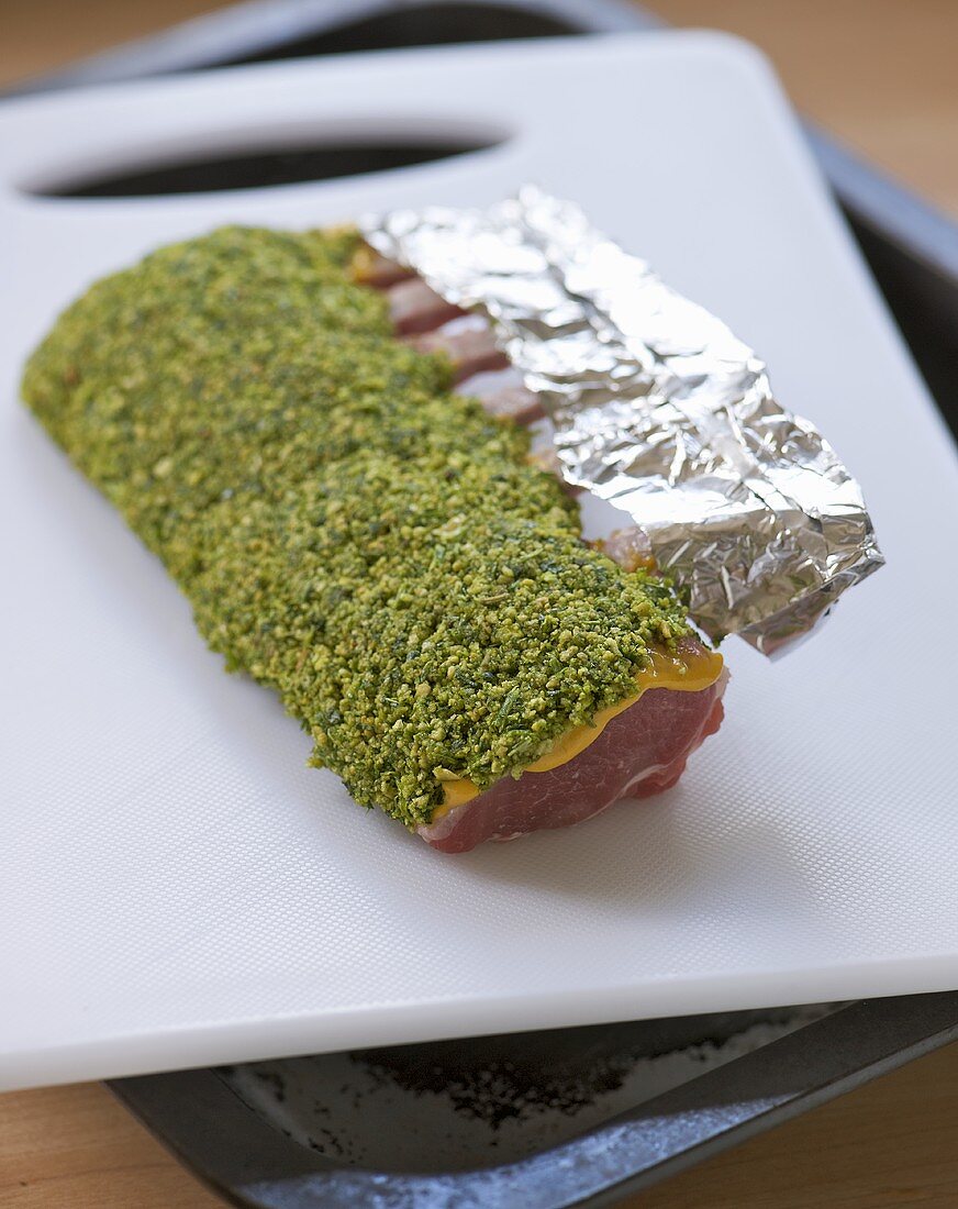 Raw rack of lamb coated with mustard and pistachios