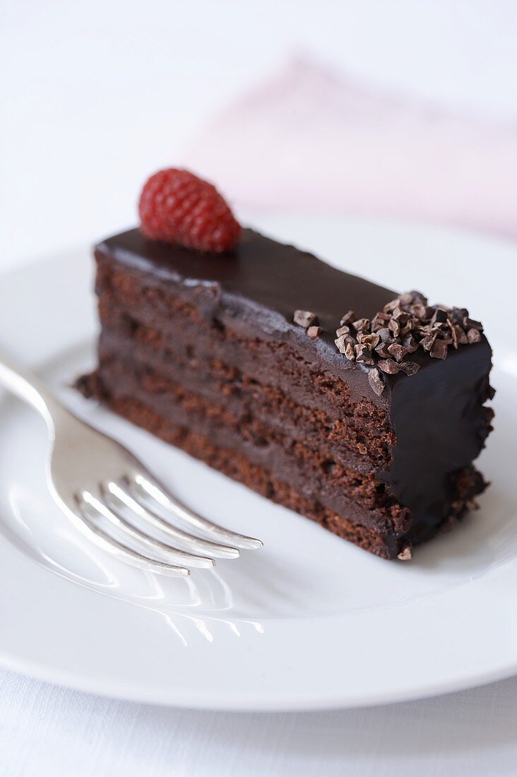 A piece of chocolate cake on a plate with cake fork