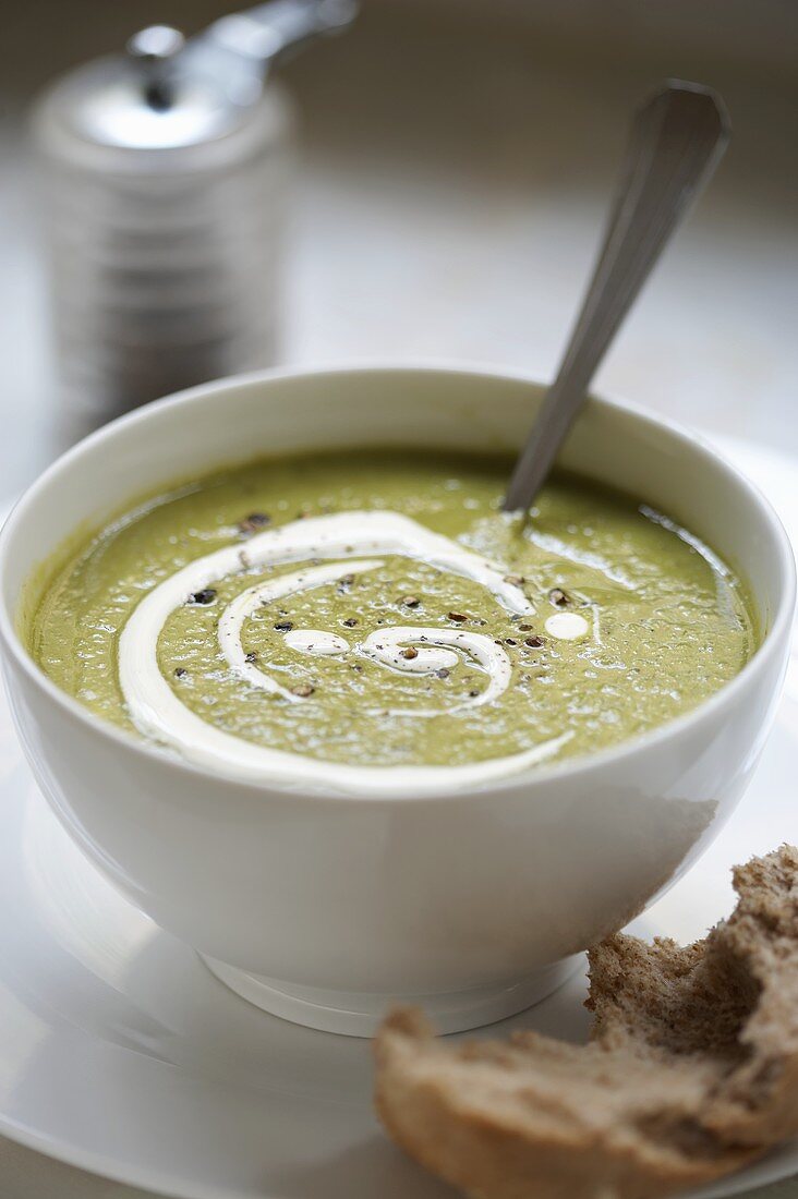 Pea soup with pesto in a soup bowl with bread