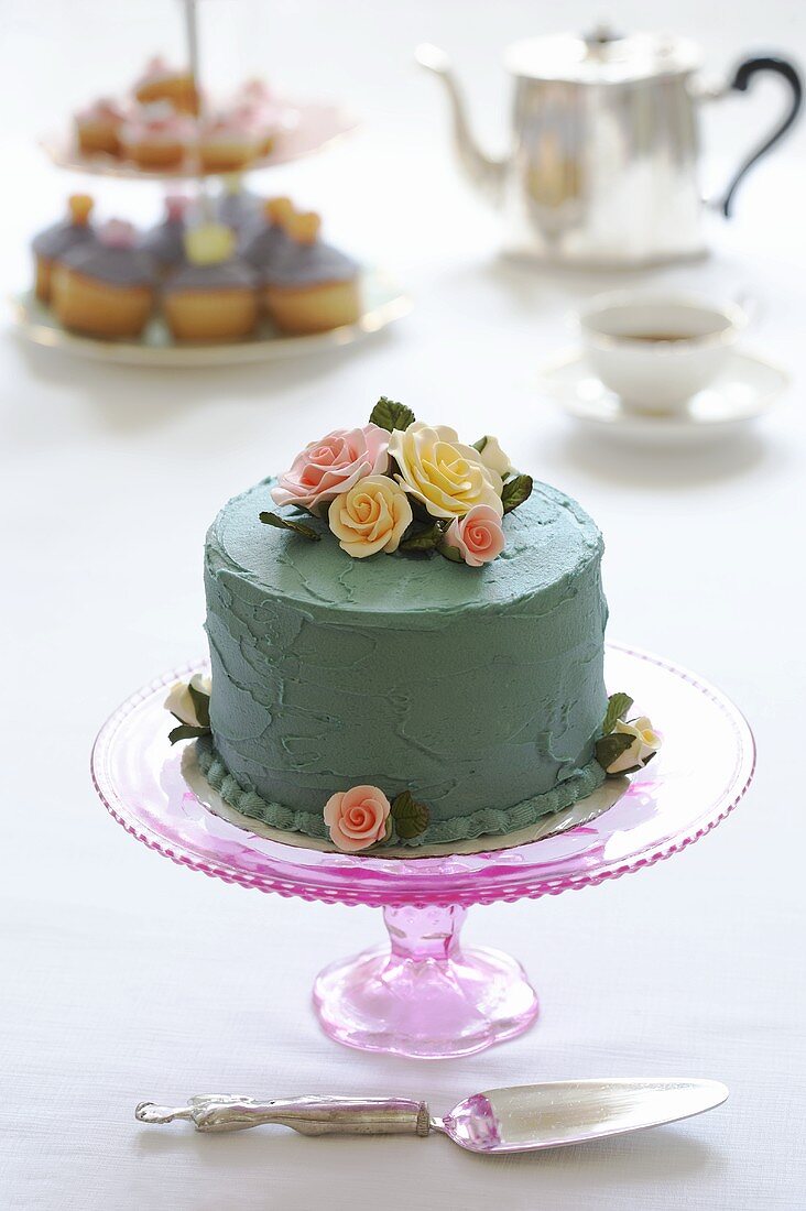 Biskuittorte mit blauer Creme überzogen und Zuckerrosen