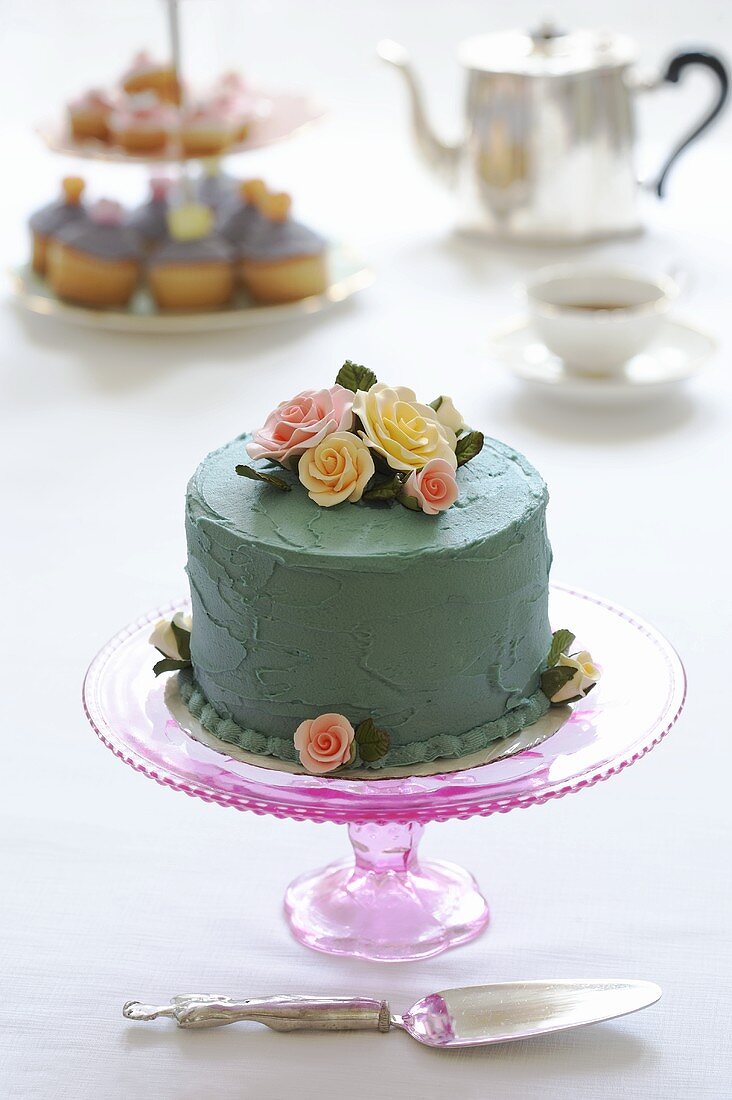 Sponge cake covered in blue cream & decorated with sugar roses