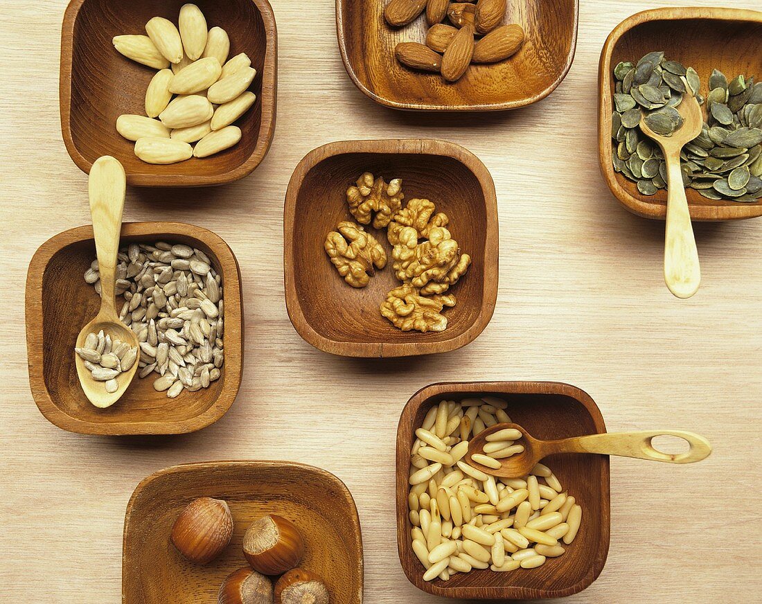 Various nuts in wooden bowls with wooden spoons