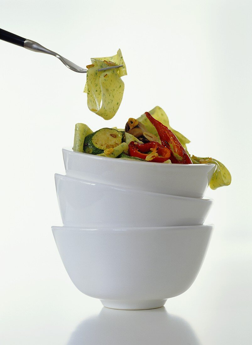 Kräuter-Bandnudeln mit Gemüse in gestapelten Schüsseln
