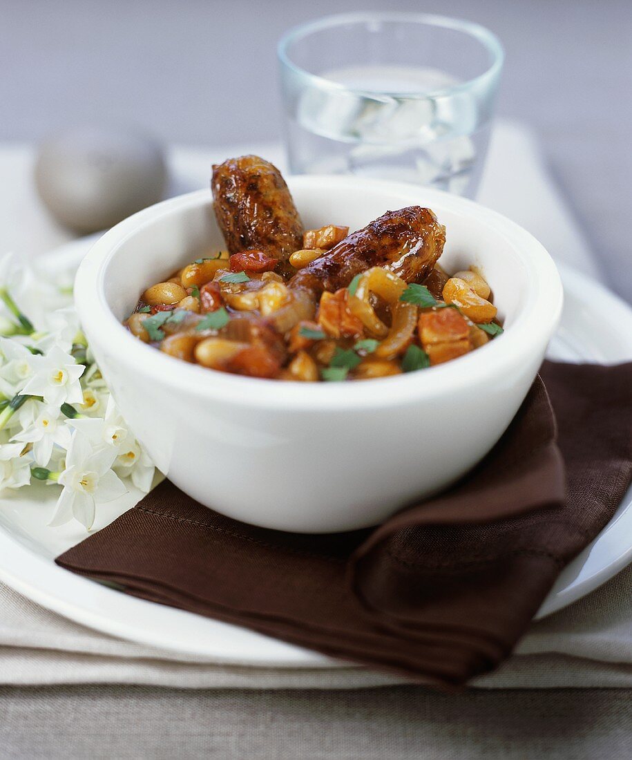 Bean stew with fried sausages in a bowl