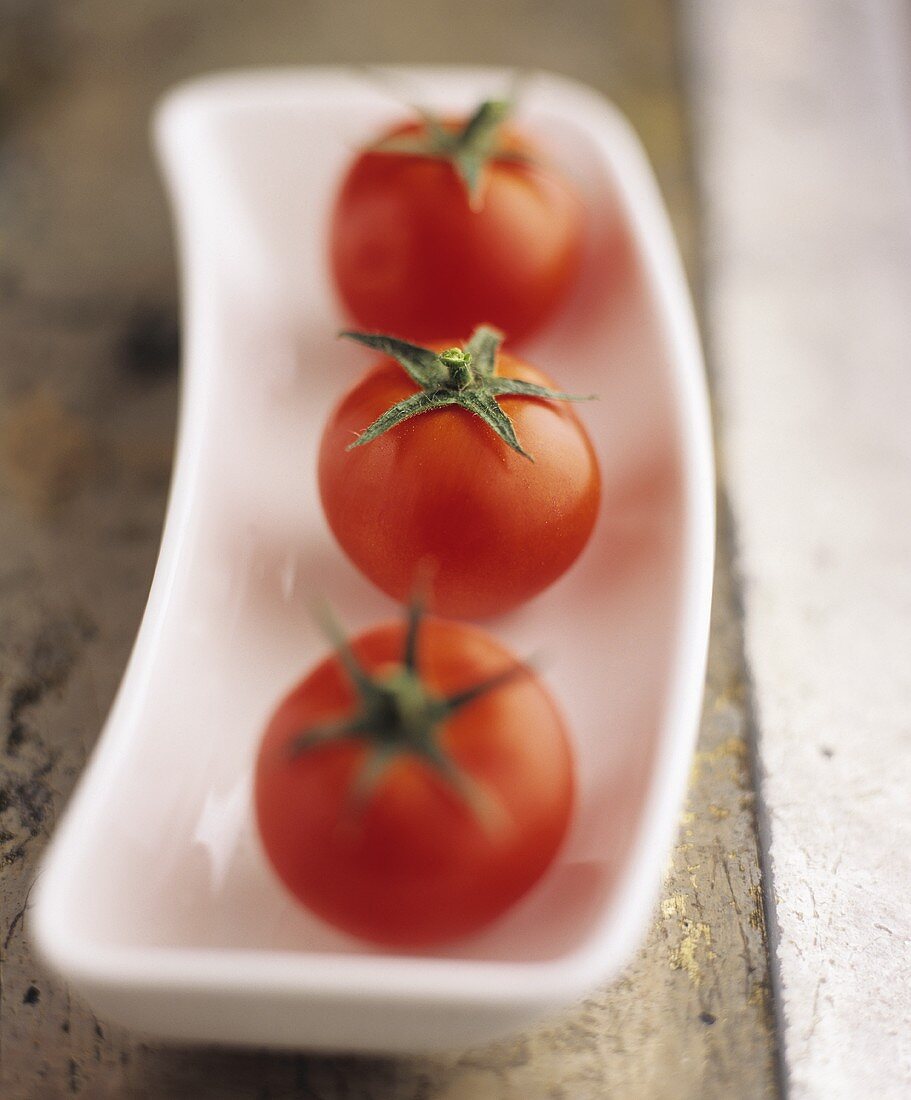 Three cocktail tomatoes in a porcelain dish