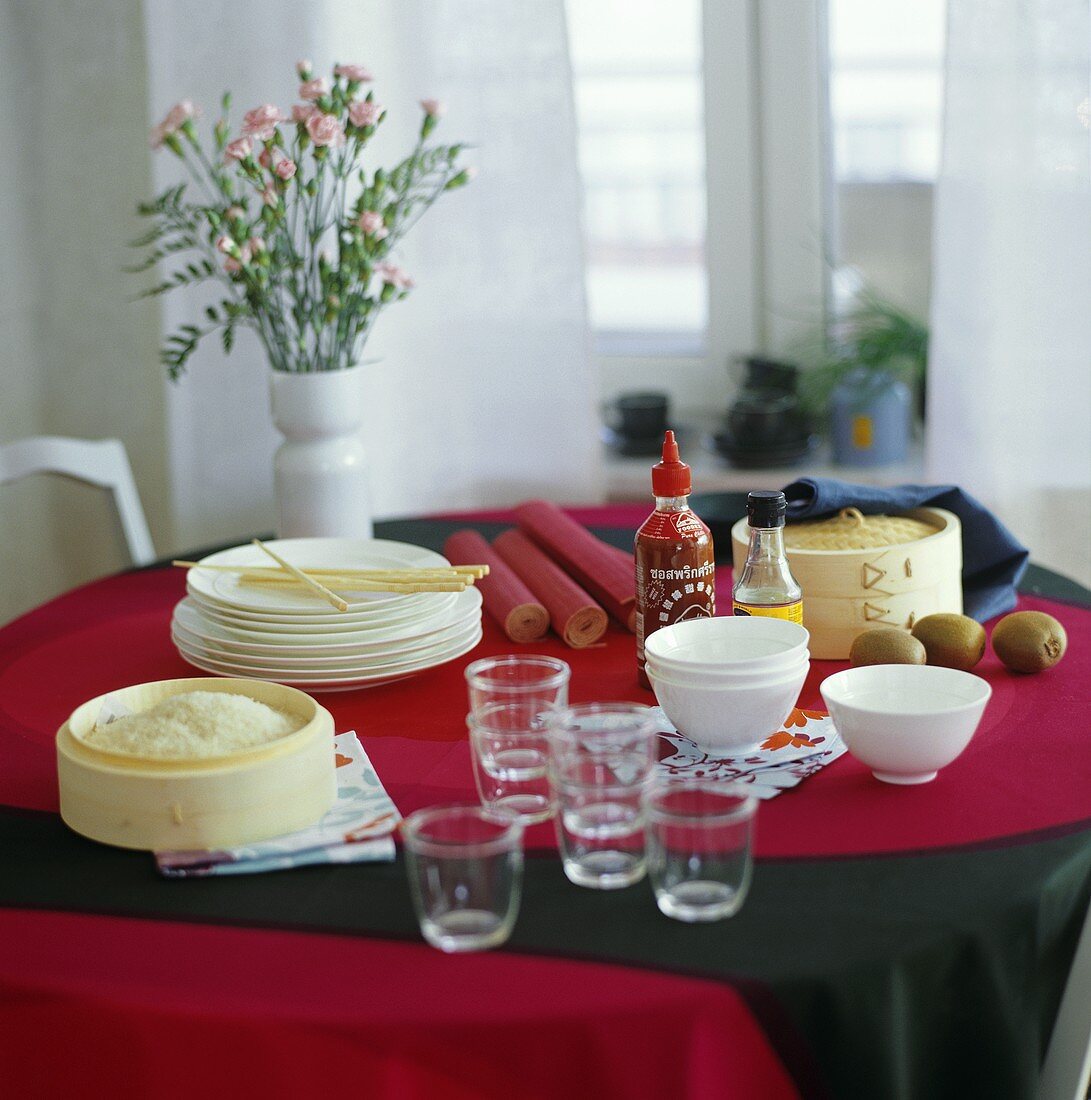 Laid table with bamboo steamer, rice and tableware